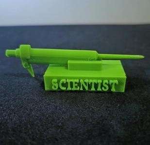 Sculpture with a replica of a micropipette and the word "Scientist"