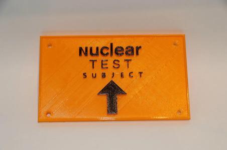 A funny sign that says "nuclear test subject" with and arrow   