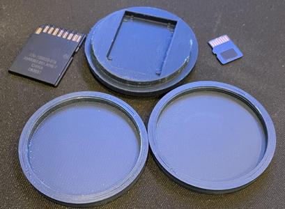 Small circular screw on case that holds an SD Card and 4 MicroSd Cards.