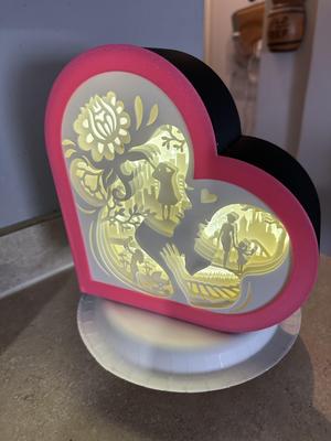 Woman holding daughters hand inside a heart shadow box