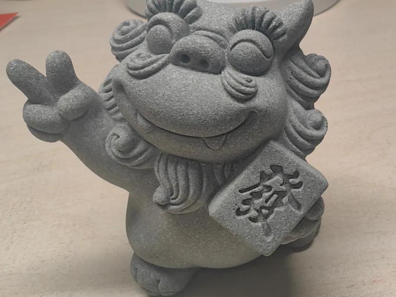Small lion figurine, a symbol of prosperity and good fortune, with a smiling face and holding a plaque with the character "发" (fa) which symbolizes wealth and fortune.