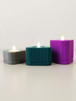 Candle holder with ribbed texture and triangular shape.