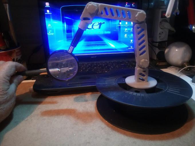Hinged magnifying glass holder on a reel support