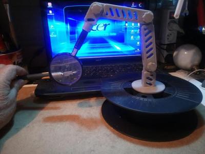 Hinged magnifying glass holder on a reel support
