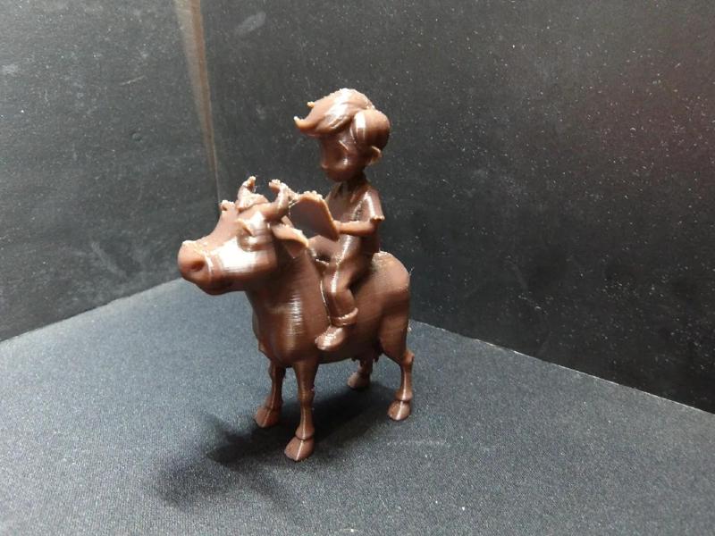 A young boy reading a book on a cow.   