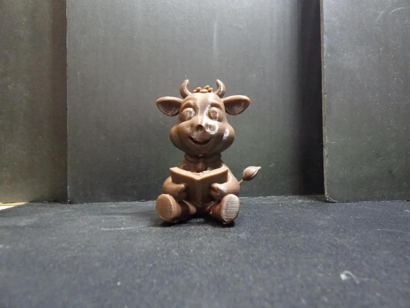 A cute cartoon cow reading a book.   