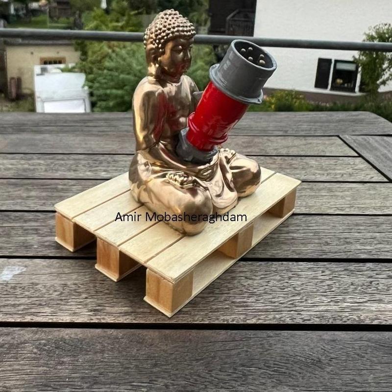 Ein goldener Buddha sitzt entspannt auf einer Palette – in seiner Hand hält er einen MENNEKES PowerTOP Stecker.