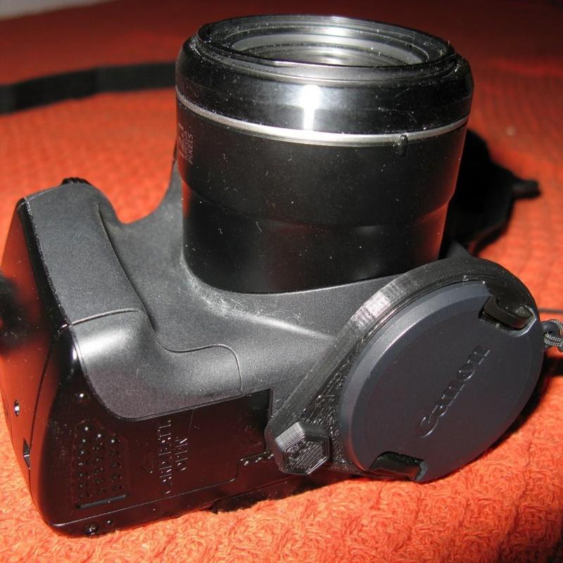 Lens cap holder screwed to camera bottom