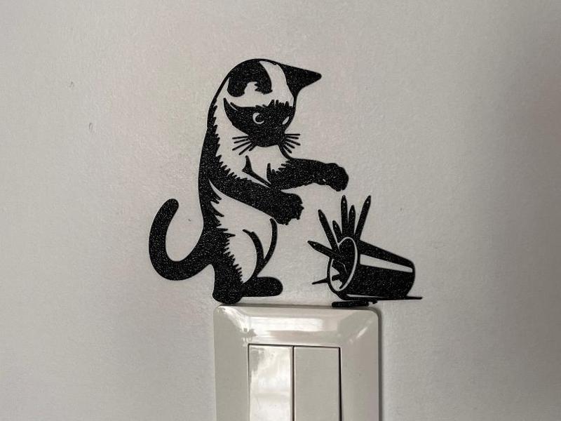 A cat playing with a box of pencils
