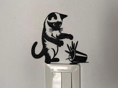 A cat playing with a box of pencils