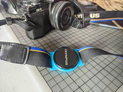 Camera lens cap strap holder