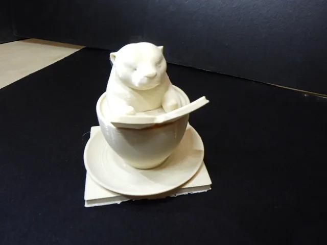 A cute otter sitting in a coffee cup reading a book.   