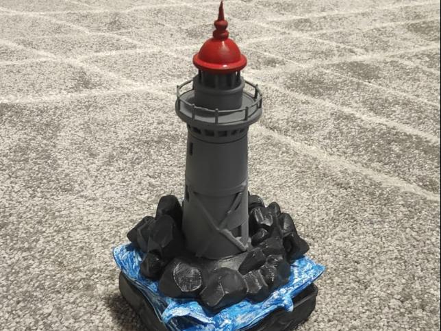 Small diorama of a lighthouse on rocks at sea